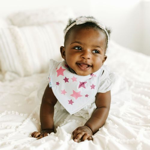 Baby Mädchen trägt Dotty Fish weiß Baumwolle Bandana Lätzchen mit rosa Sternen Muster.