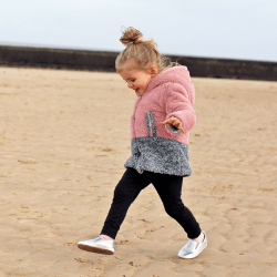 Kleines Mädchen am Strand mit Dotty Fish silbernen Lederschuhen mit Gummisohle zum Hineinschlüpfen.