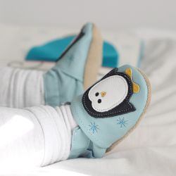 Babyjunge trägt mintgrüne Dotty Fish-Schuhe mit weiß-schwarzem Pinguin-Design.